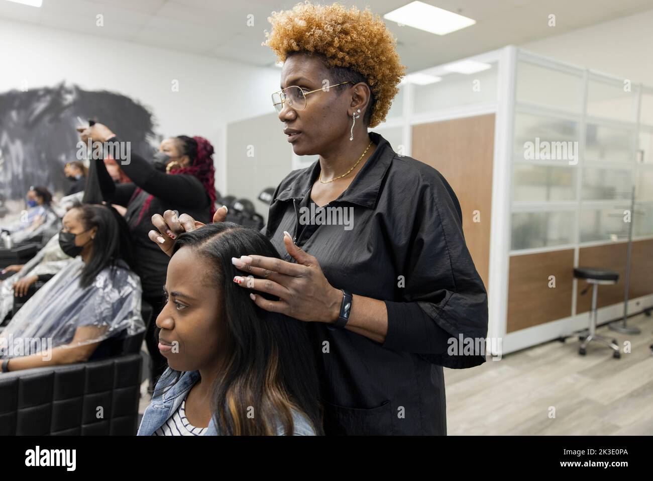 Woman getting hair done by hairstylist in hair salon Stock Photo Alamy