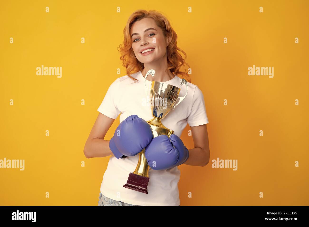 Woman in boxing gloves hold champion winner cup trophy. Winner female