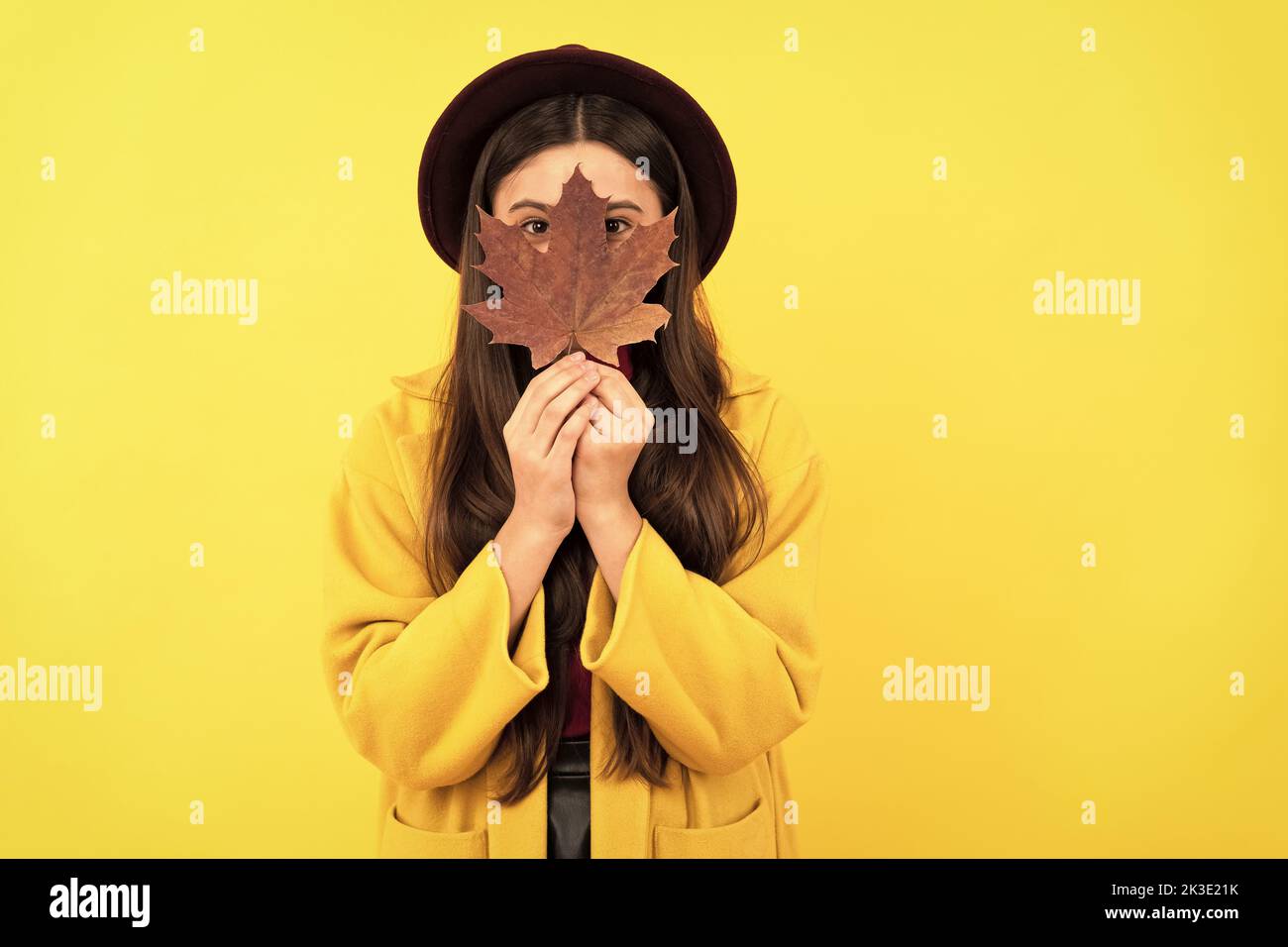 funny teen girl in hat and coat hiding behind autumn maple leaf on ...
