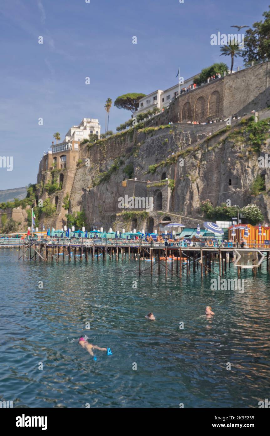 Tourists swimming and sunbathing at a private lido beach resort in the