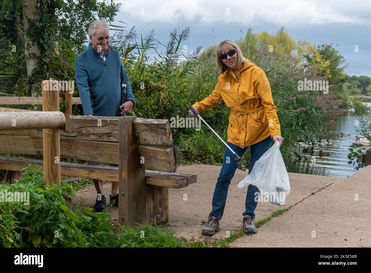 Senior couple litter picking, litter pickers tidying up countryside