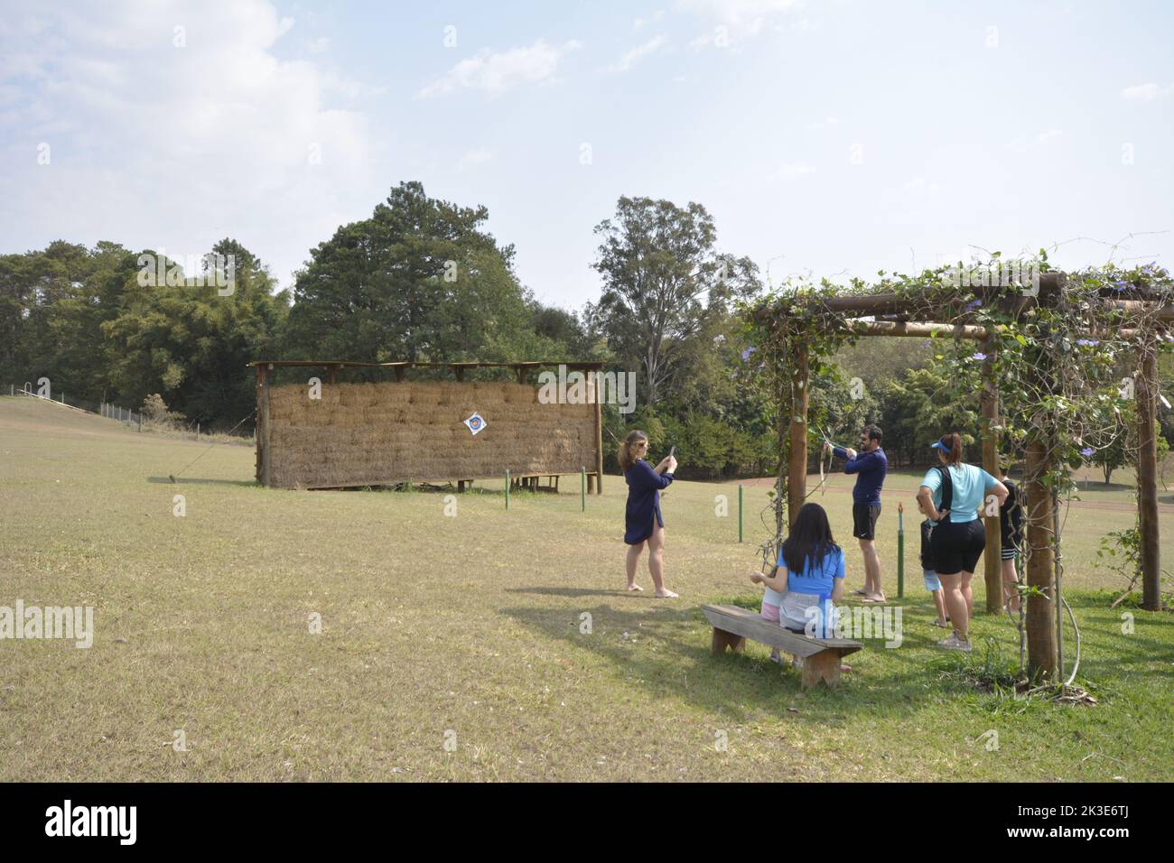 Tourists at an ecotourism farm practicing archery with monitors watching. panoramic. wide angle Stock Photo