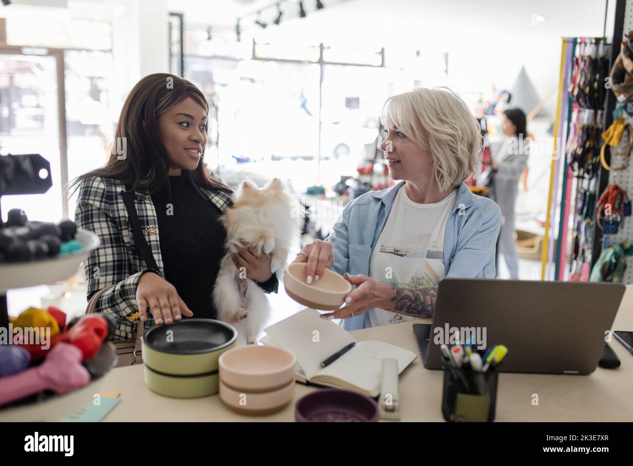 Female business owner helping customer with dog shopping in pet store