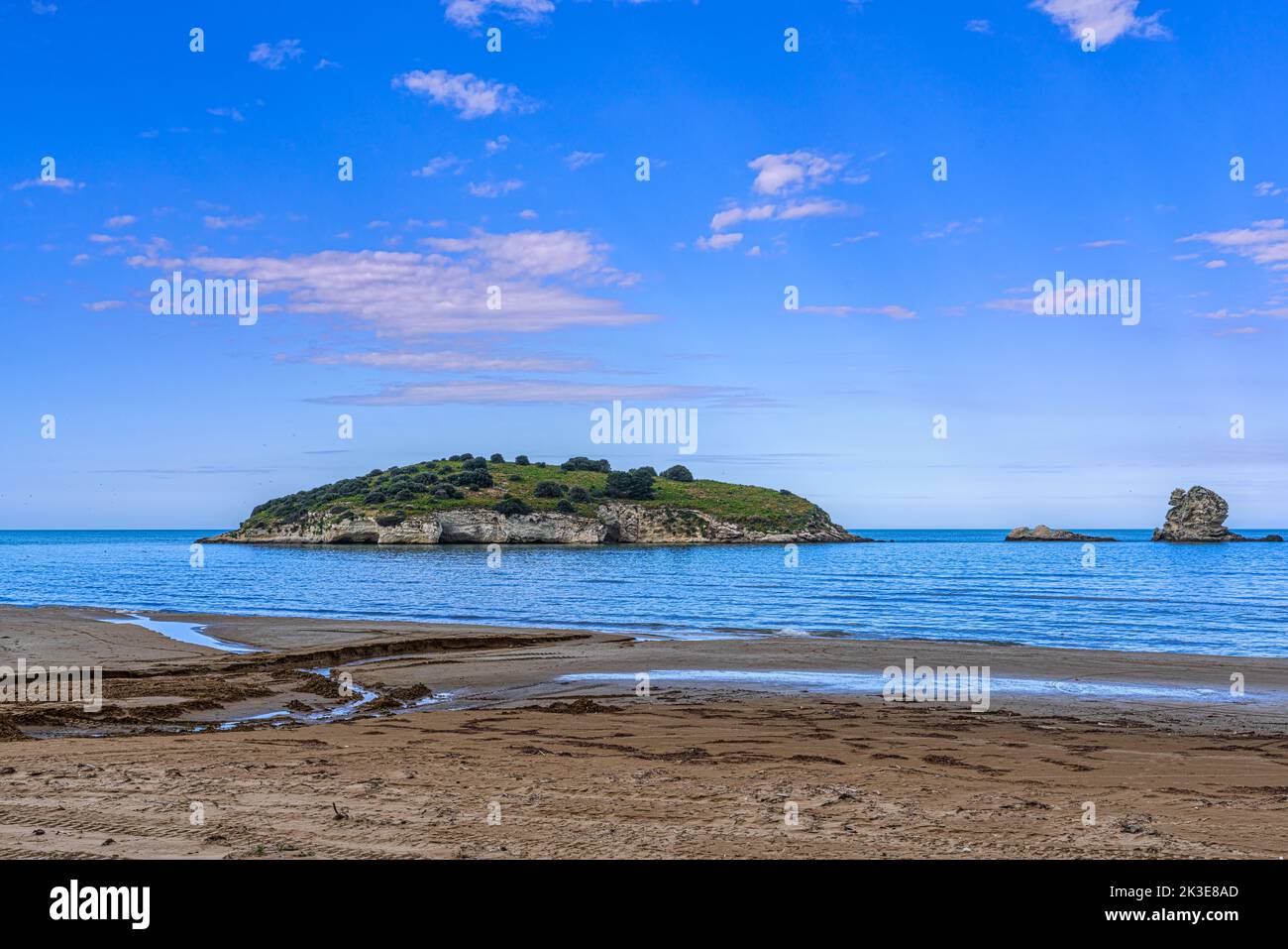 The islet and rock of Portonuovo, in the Gargano coast near the tourist town of Vieste seen from the sandy beach of Portonuovo, Vieste, Puglia Stock Photo