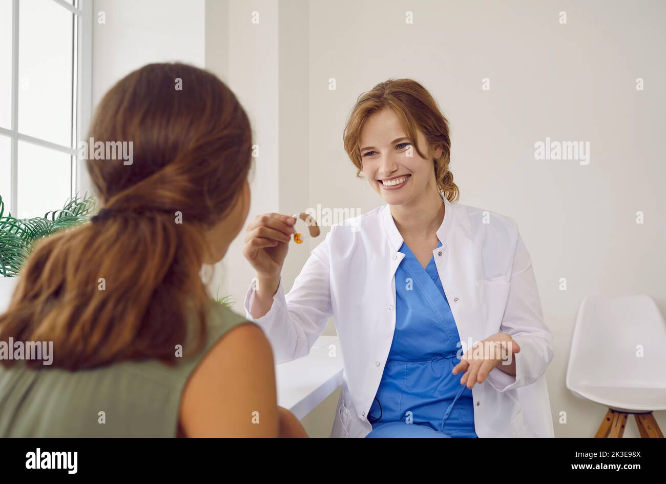 Happy, smiling audiologist gives modern hearing aid to child with hearing impairment Stock Photo
