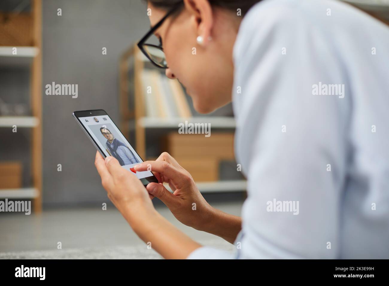 Business woman giving a like to man's photo in mobile dating app on smartphone screen. Stock Photo