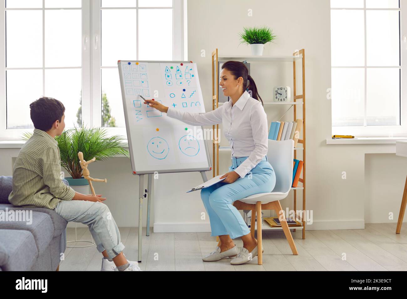 Friendly female psychologist conducts psychological tests with preteen boy in her office. Stock Photo