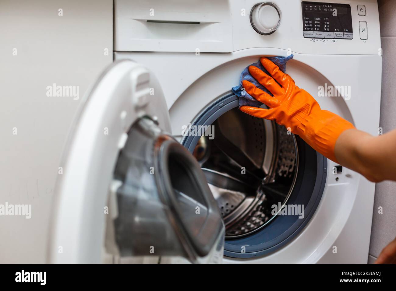 Hand in torn glove cleaning the washing machine. Regular clean up. Maid