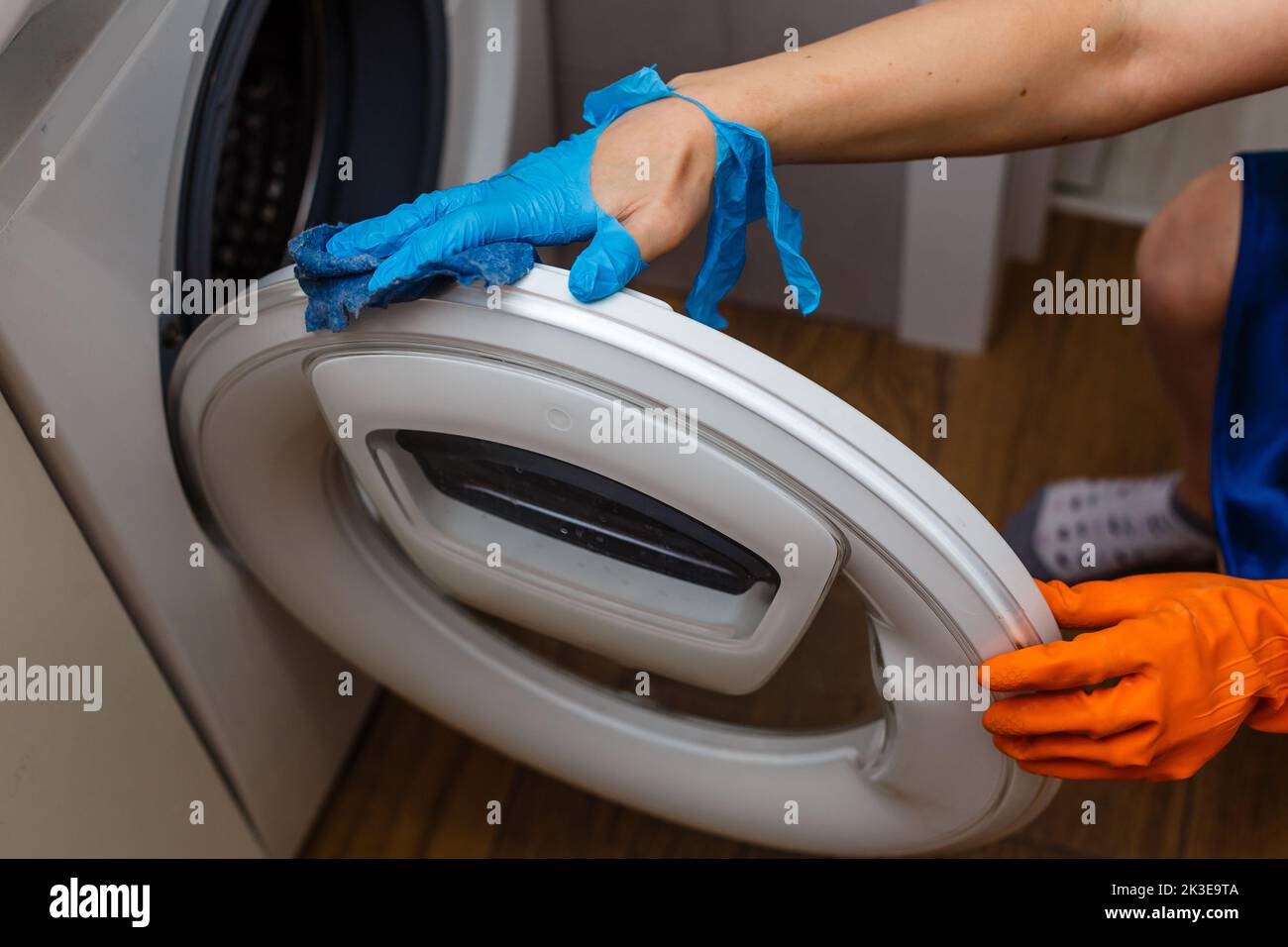 Hand in torn glove cleaning the washing machine. Regular clean up. Maid