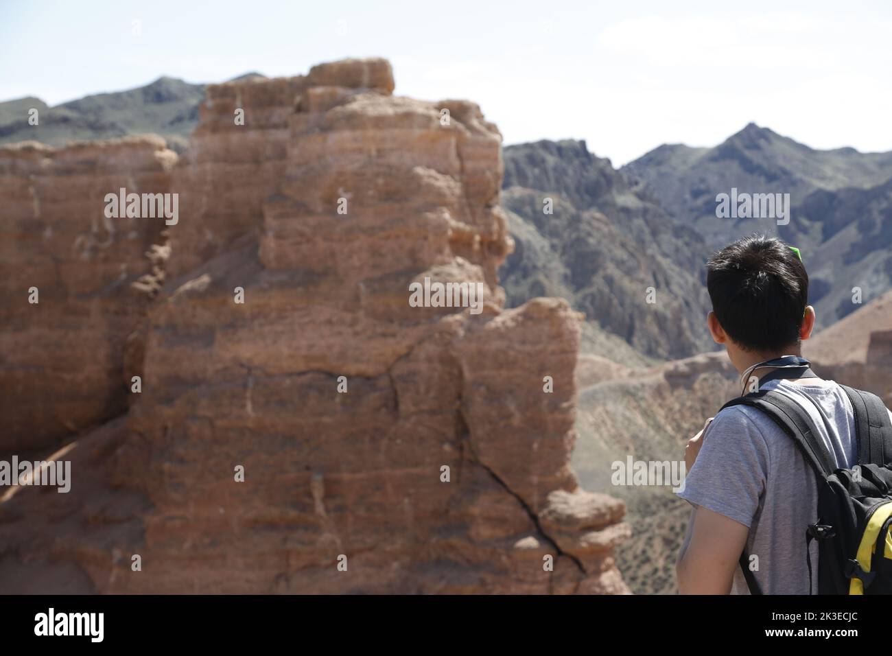 Male with backpack (a tourist?), seen from the back, looking at the impressive,majestic landscape in Charyn Canyon National Park, Kazakhstan Stock Photo