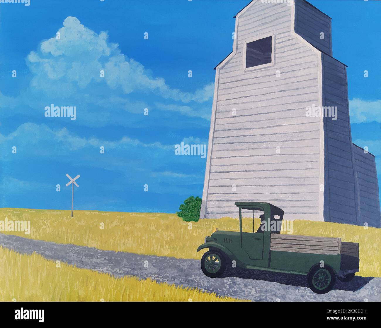 Vintage scene of an old green pick-up truck passing by a large white grain elevator on the Canadian prairies. Stock Photo