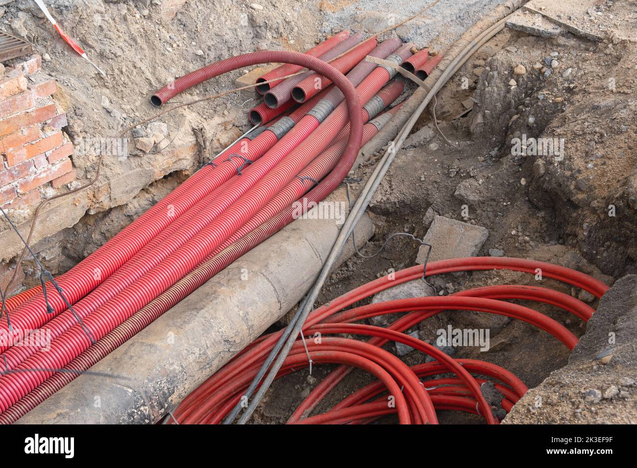 Network cables in red corrugated pipe are buried underground on the