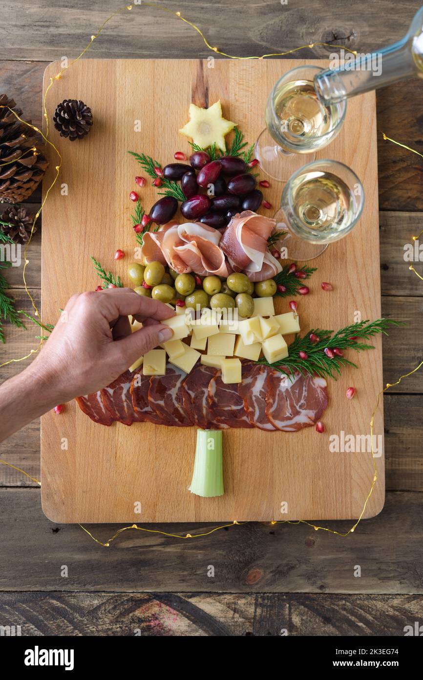 Cheese and charcuterie board in the shape of a Christmas tree. Two people  eating. Copy space. Top view Stock Photo - Alamy