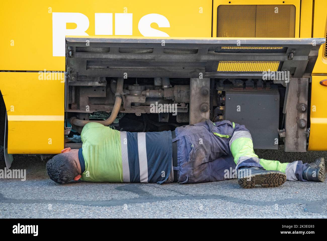 Machanic working on a broken down bus with engine visible Stock Photo
