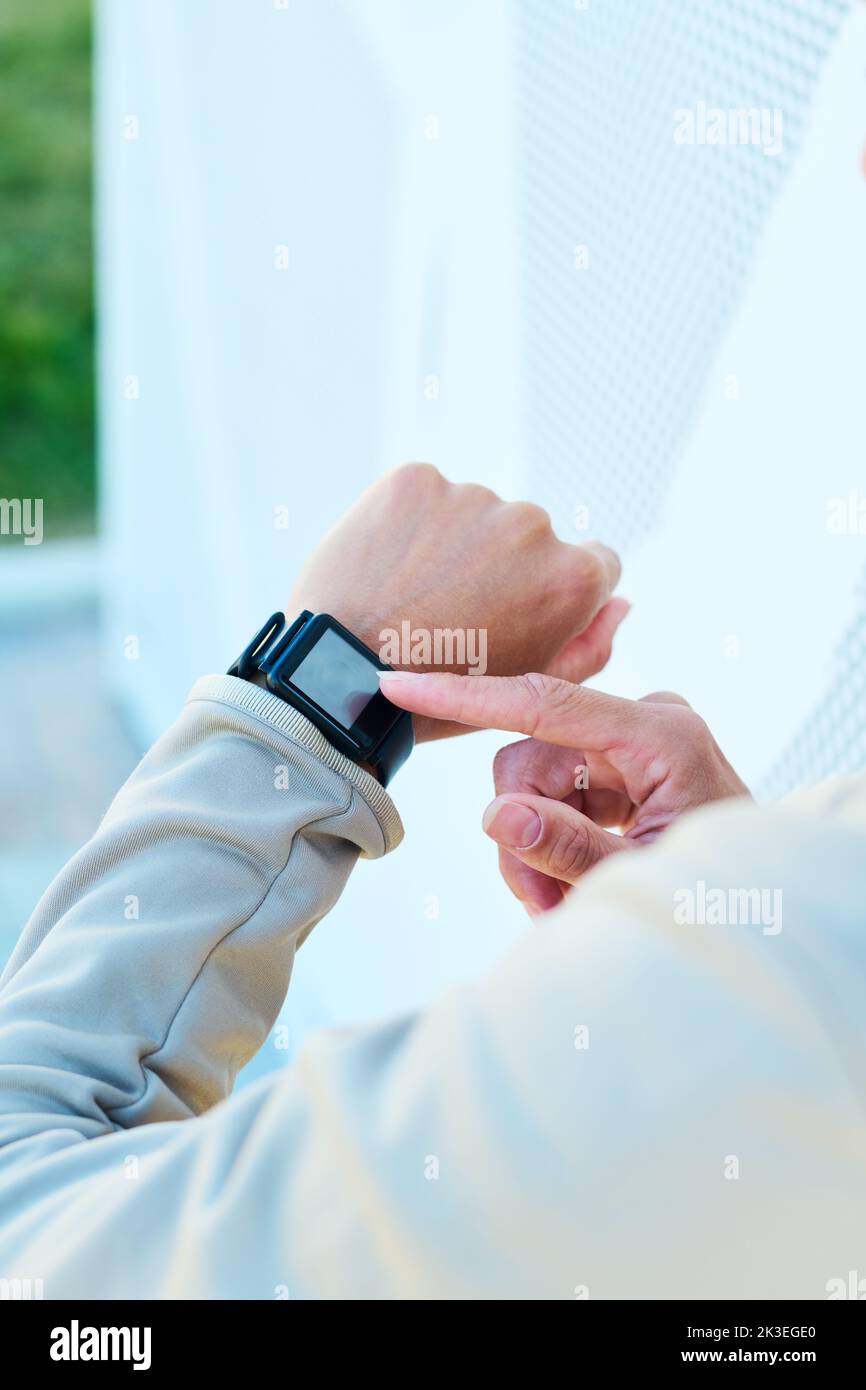 Hand of young modern sportswoman pointing at small square screen of smartwatch on her wrist while noting time before training Stock Photo
