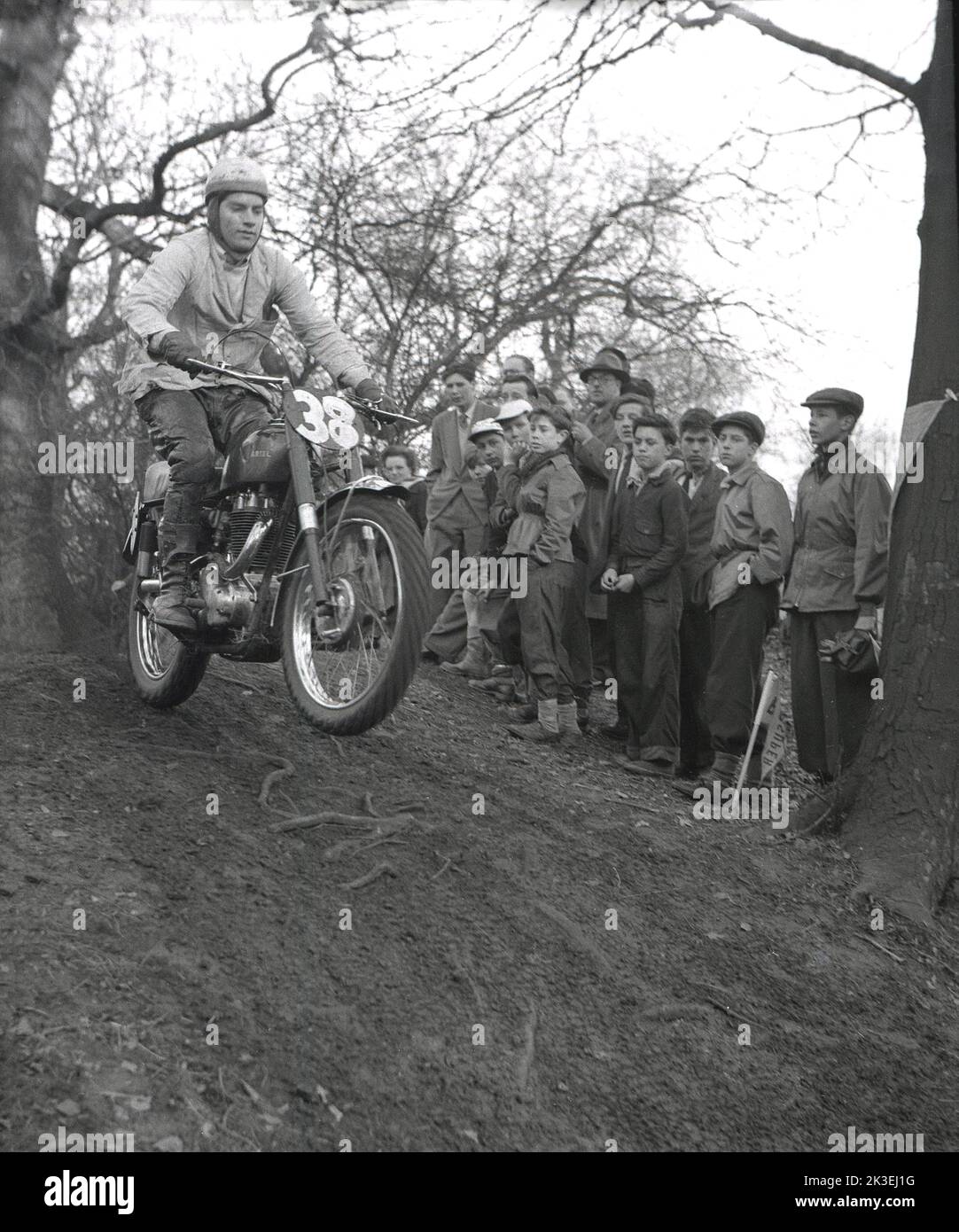 1954, historical, outside on rough terrain in a forest, spectators watching competitor 38 riding a motorcycle of the era, possiblly an Ariel, in a scramble or trial race at Seacroft, Leeds, England, UK, organised by the West Leeds Motor Club. Stock Photo