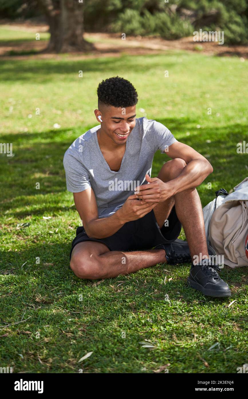 Sporty satisfied meloman chilling in sunny park Stock Photo