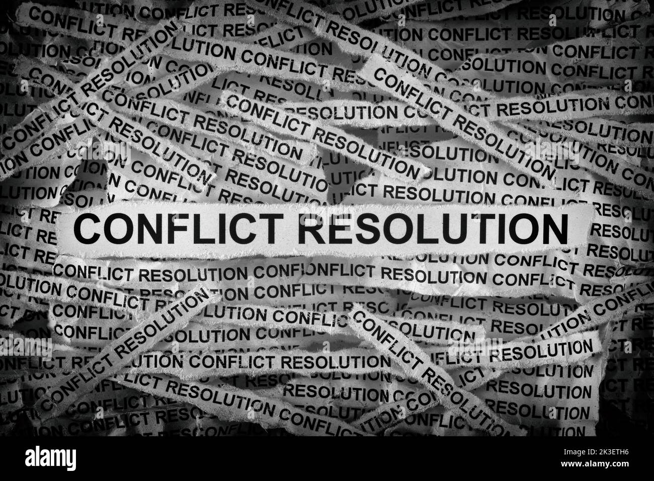 Strips of newspaper with the words Conflict Resolution typed on them. Black and white. Close up. Stock Photo
