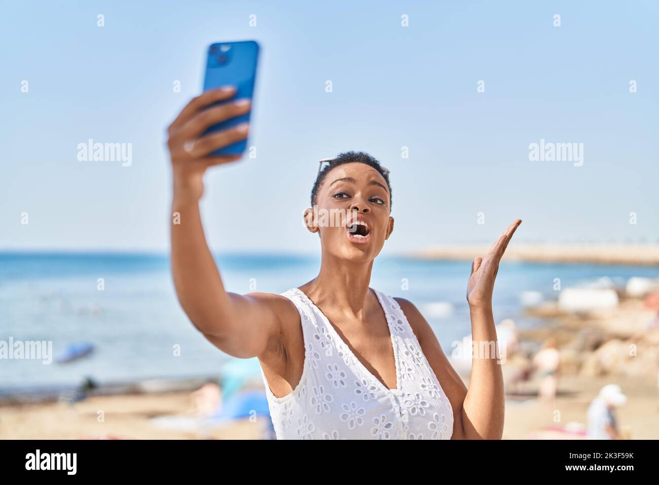 African american woman smiling confident having video call at seaside ...