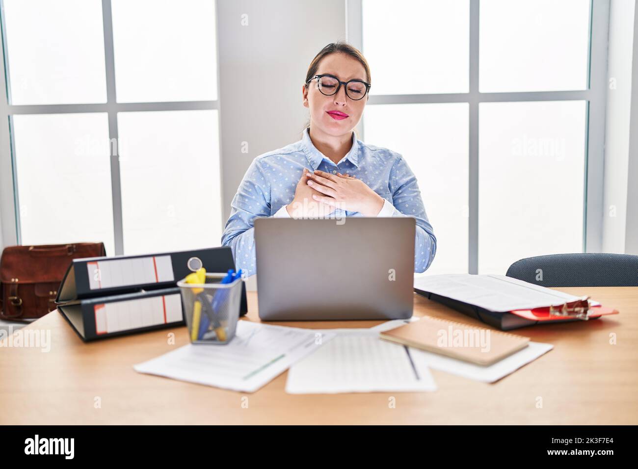 Young hispanic woman working at the office wearing glasses smiling with ...