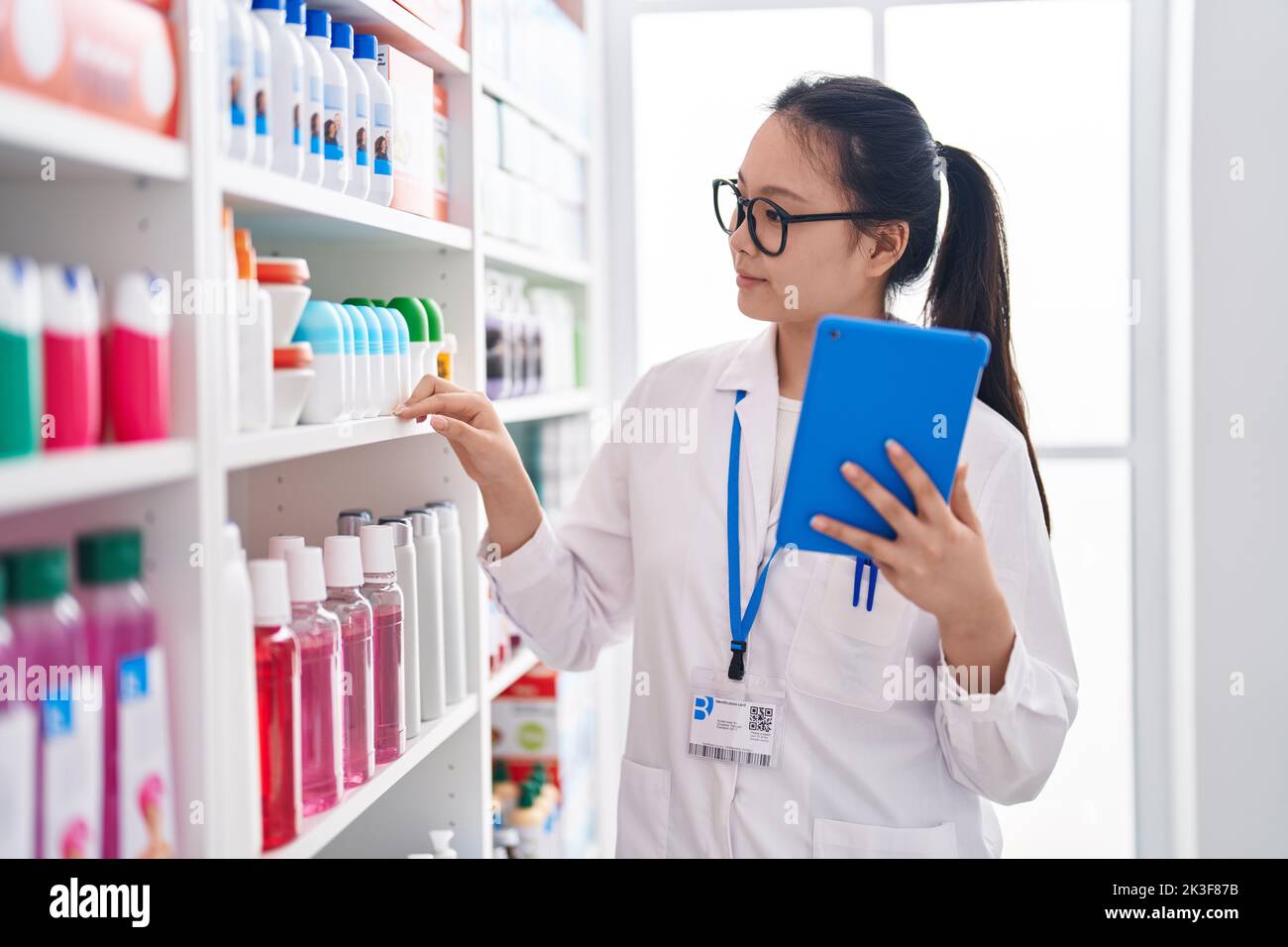 Young chinese woman pharmacist using touchpad working at pharmacy Stock ...