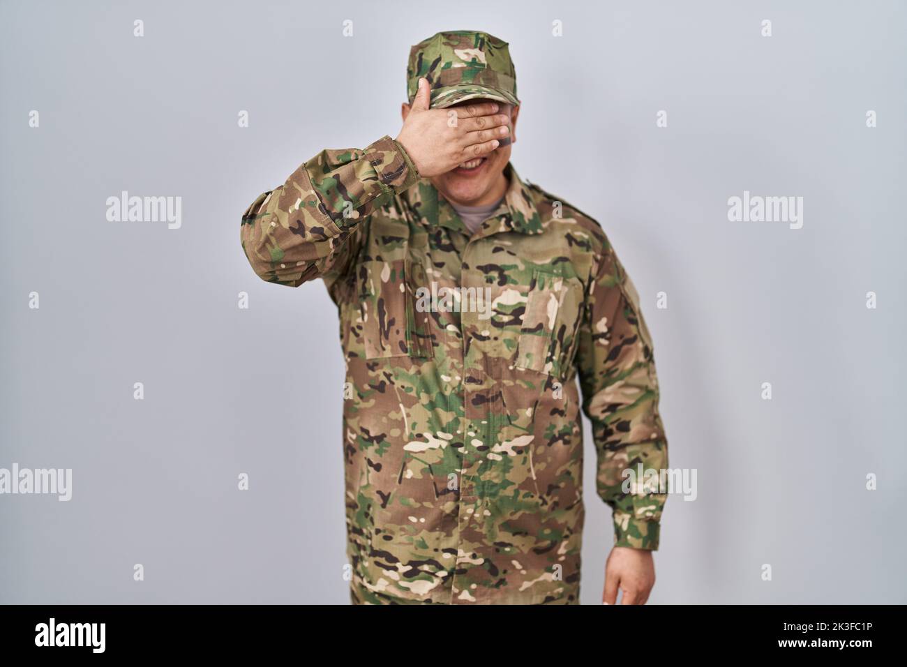 Hispanic young man wearing camouflage army uniform smiling and laughing ...