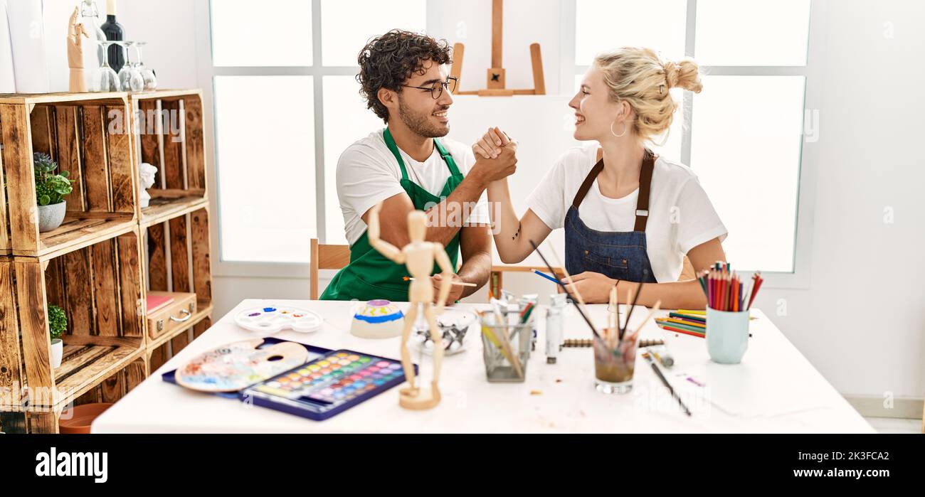 Young artist couple smiling happy shaking hands at art studio. Stock Photo
