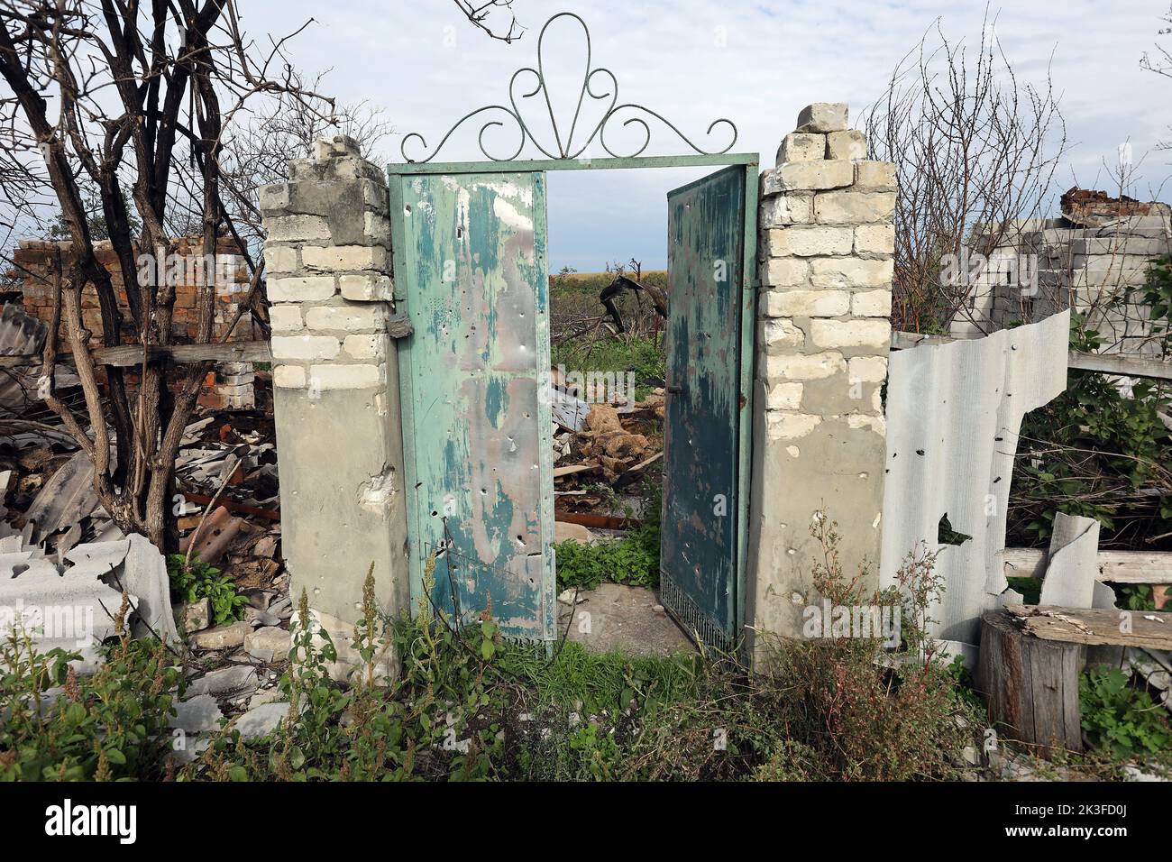 KHARKIV REGION, UKRAINE - SEPTEMBER 26, 2022 - Aftermath of hostilities in the village of Dementiyivka recently liberated from russian invaders, the gate of the destroyed fence survived, Karkiv Region, north-eastern Ukraine. Stock Photo