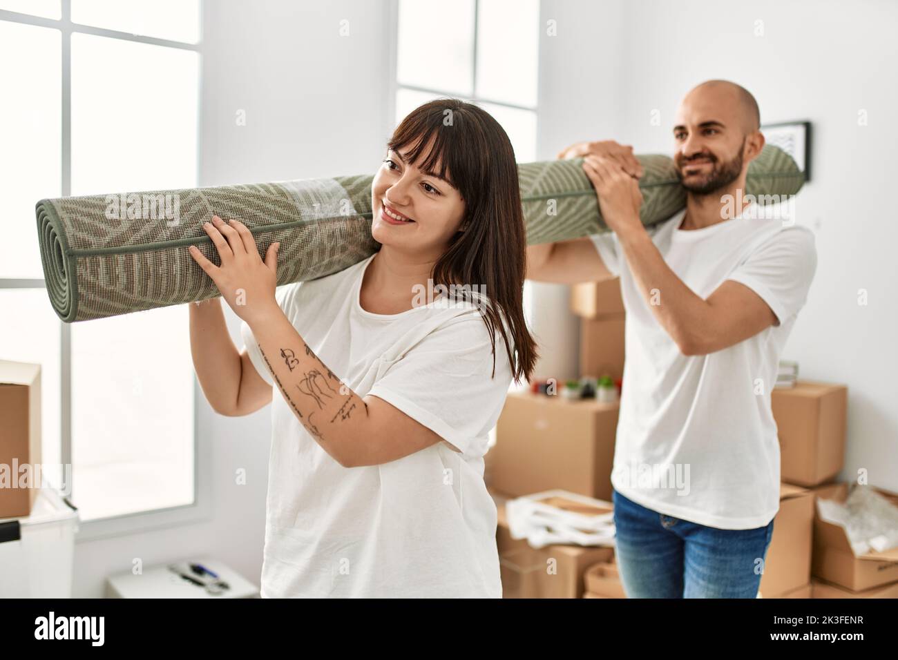 Young hispanic couple smiling happy holding carpet at new home Stock ...