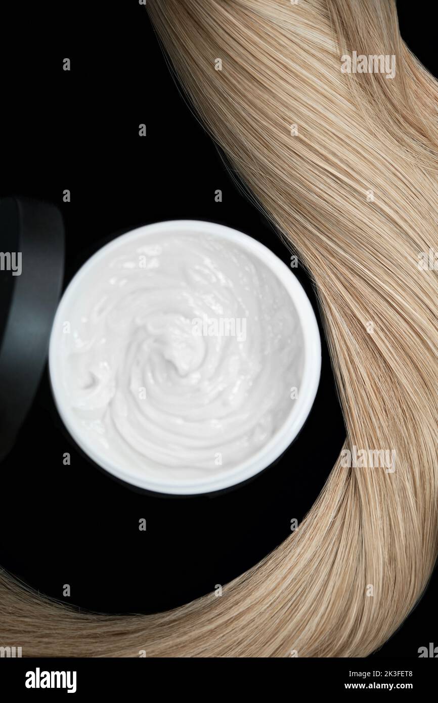 A strand of blond hair with hair balm on a black background. Close-up. Stock Photo