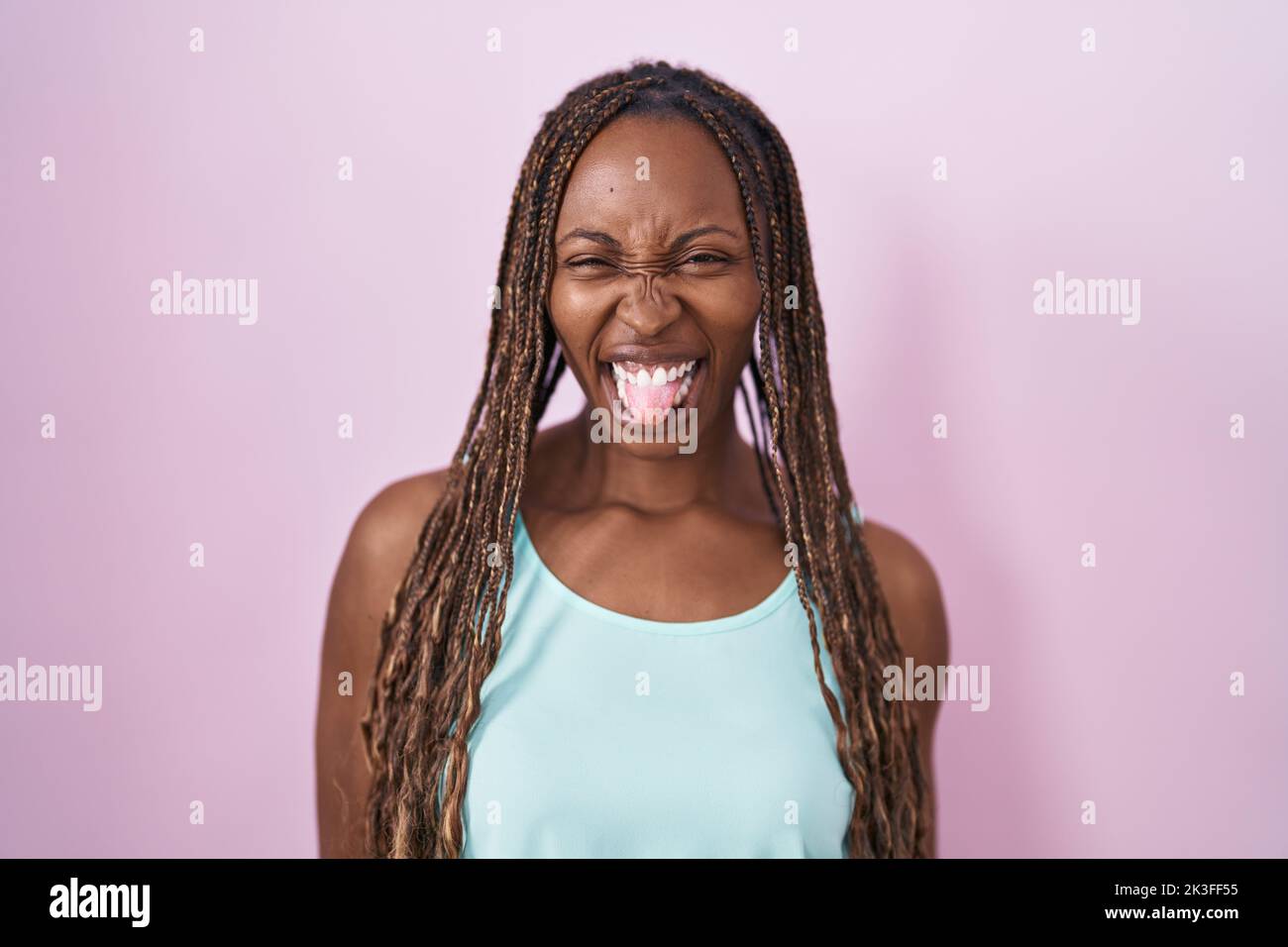 African american woman standing over pink background sticking tongue ...