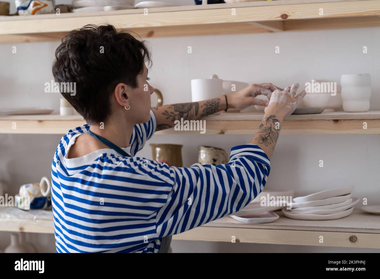 Successful ceramics studio owner arranges a showcase with finished products for sale Stock Photo