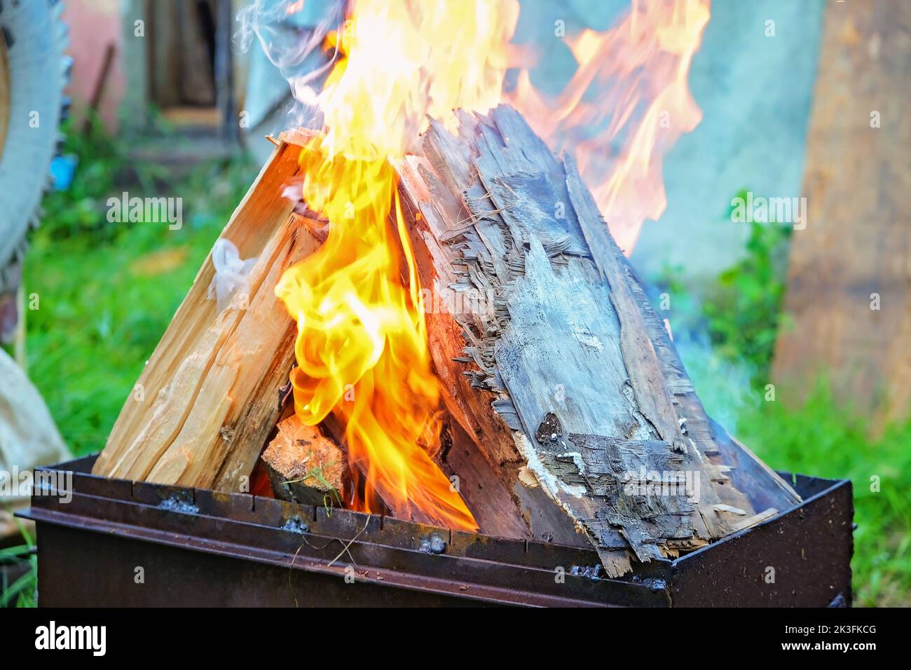Burning pine logs for coals. Strong flame on the grill. Burning firewood on the grill. The fire is burning on the grill. Stock Photo