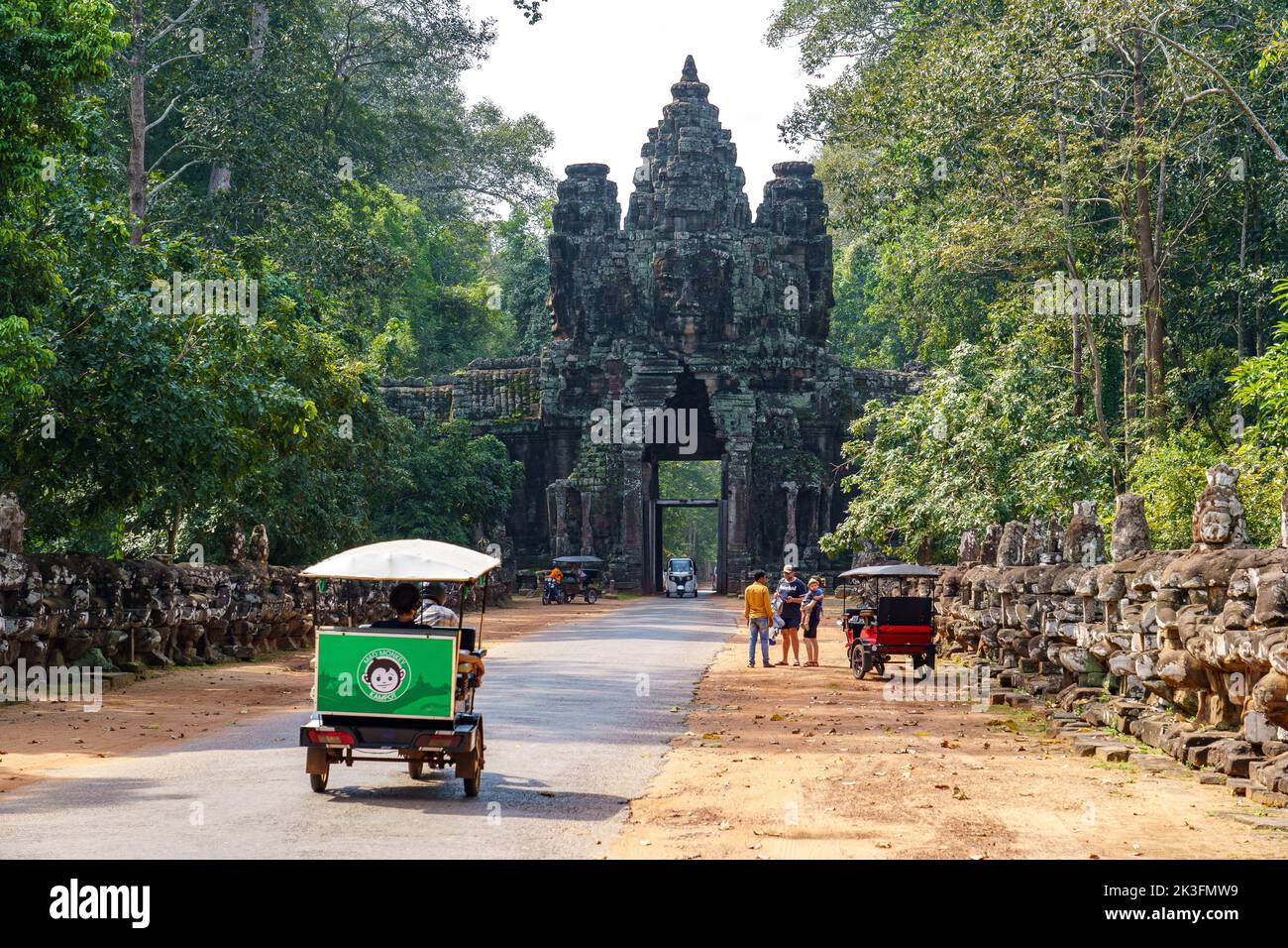 Cambodia. Siem Reap. The archaeological park of Angkor. Tuk tuk taking tourists to Bayon Temple 12th Century Hindu Temple Stock Photo