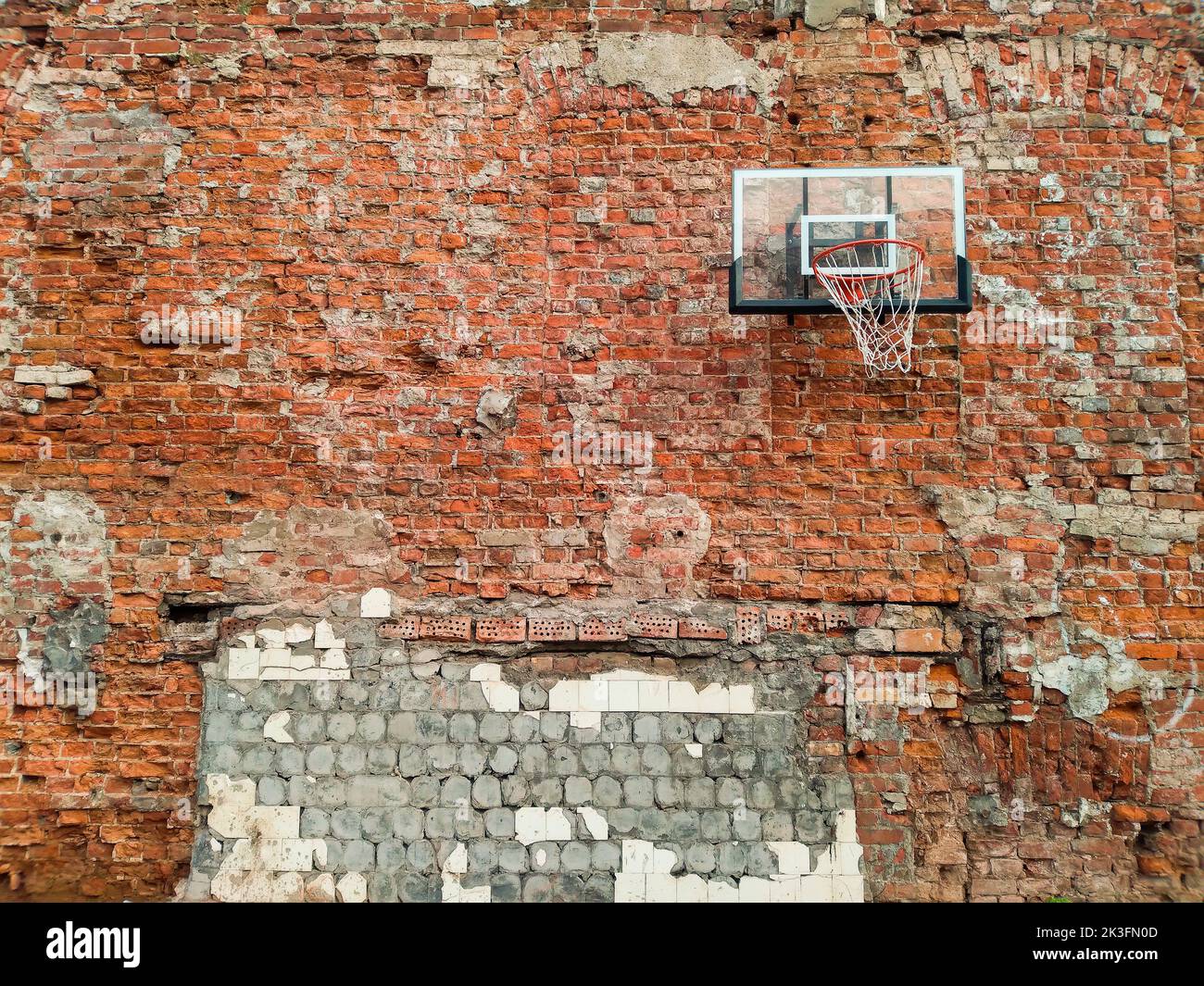 Old and worn outdoor basketball hoop net on the red brick wall