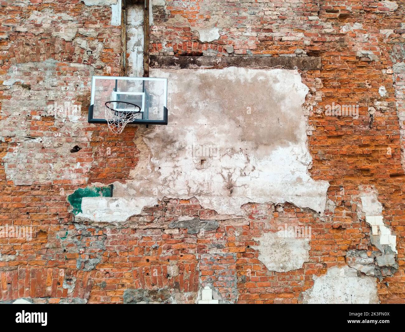 Old and worn outdoor basketball hoop net on the red brick wall