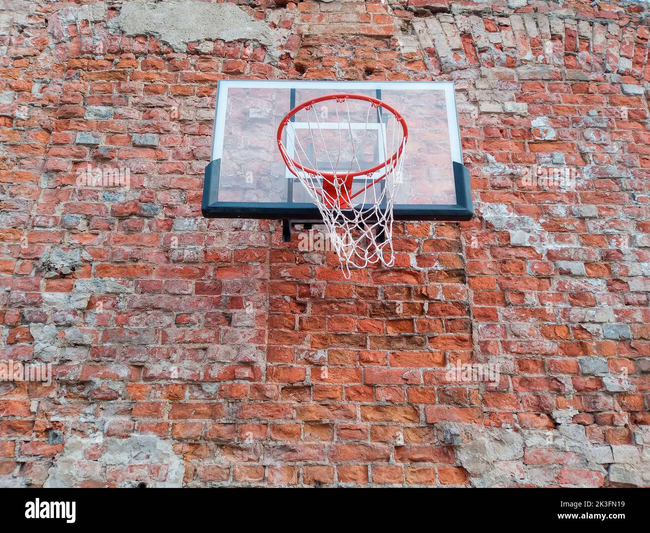 Old and worn outdoor basketball hoop net on the red brick wall