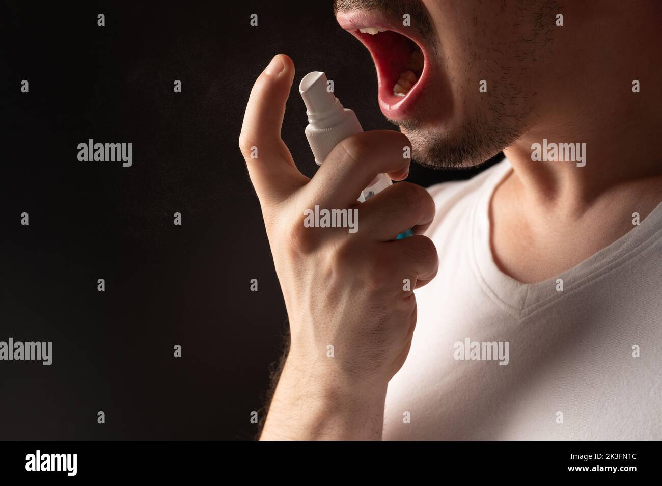 Healing pain in throat theme. Man spray his mouth Stock Photo