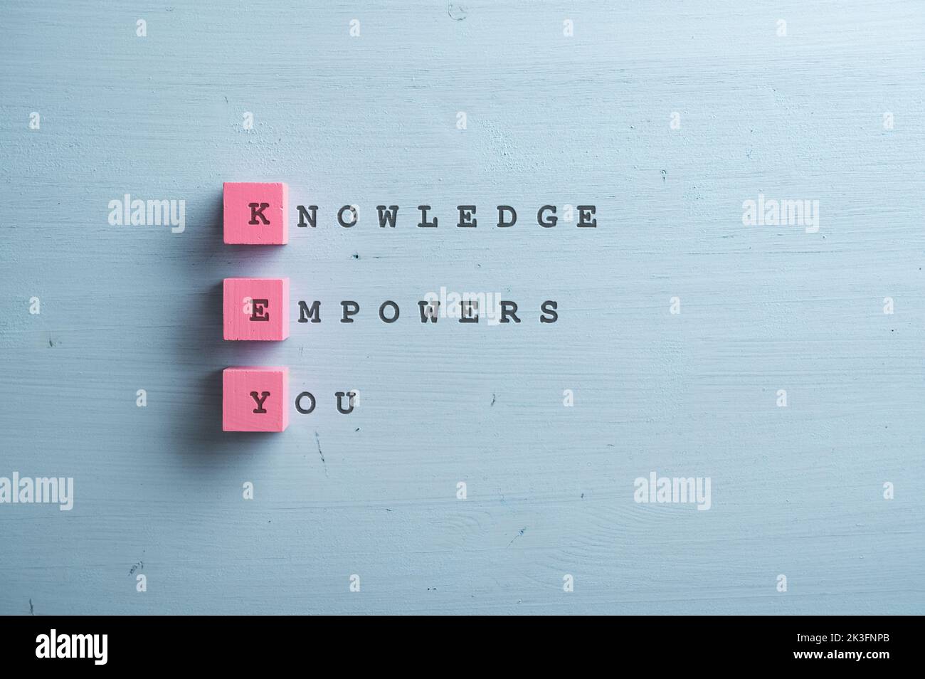Knowledge empowers you sign written on pink wooden blocks and blue wooden backgorund. Stock Photo