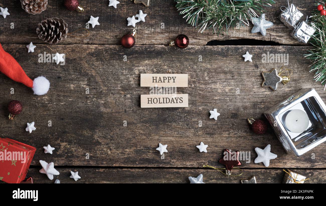 Happy holidays sign written on two wooden blocks placed on a festive christmas holidays decorated rustic wooden desk. Stock Photo