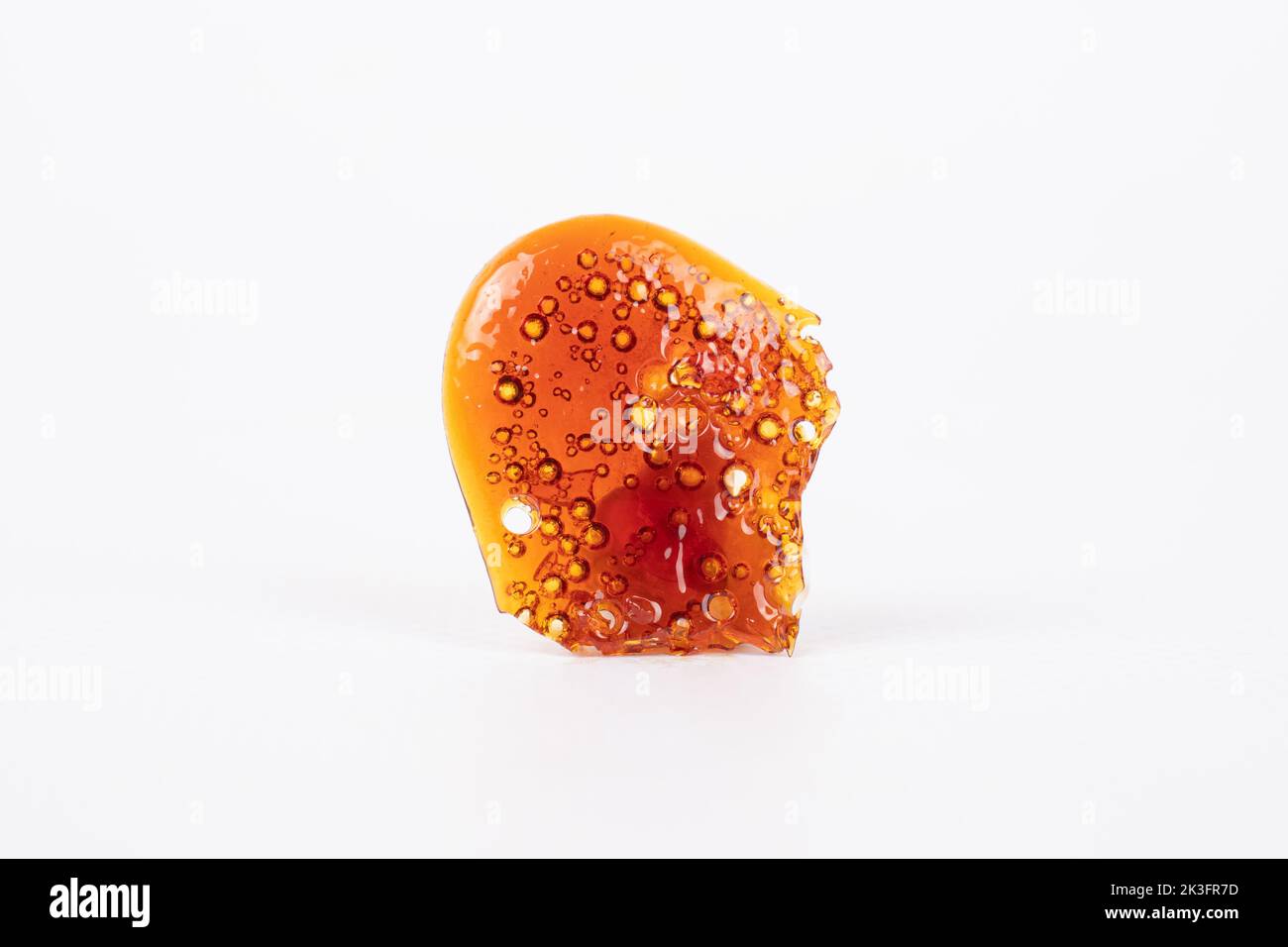 golden isolated piece of cannabis wax, shatter dab closeup. Stock Photo
