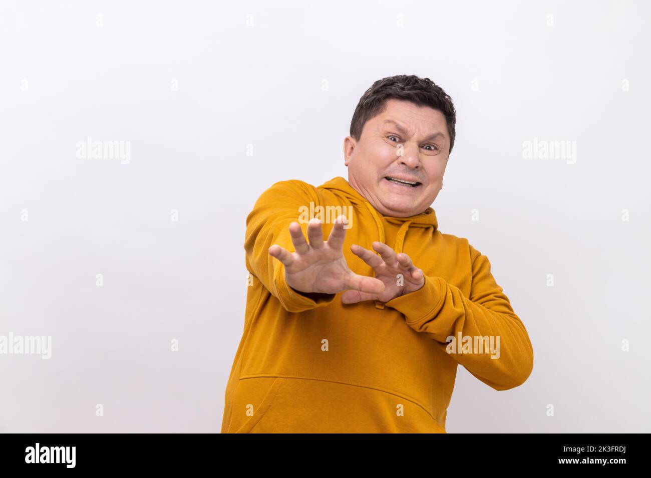 Stop. Portrait of scared man standing with afraid or worry face, looking at camera and blocking with his hands, wearing urban style hoodie. Indoor studio shot isolated on white background. Stock Photo