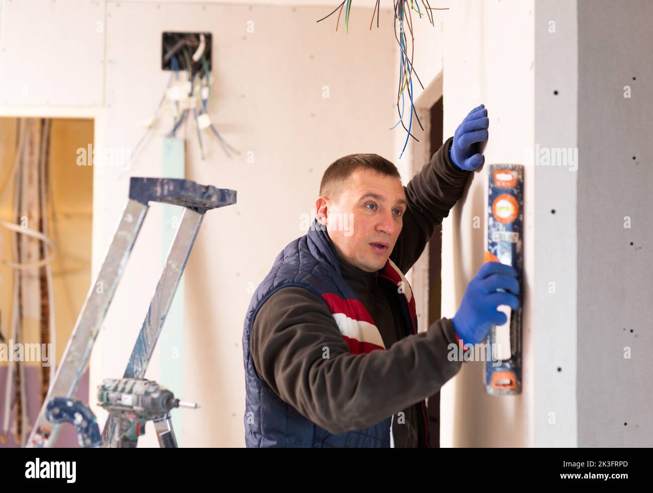 Builder Using Level Builder checks the vertical of the wall using level Stock Photo - Alamy
