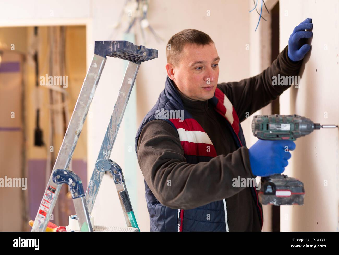 Male contractor holding electric perforator ready for construction works indoors Stock Photo