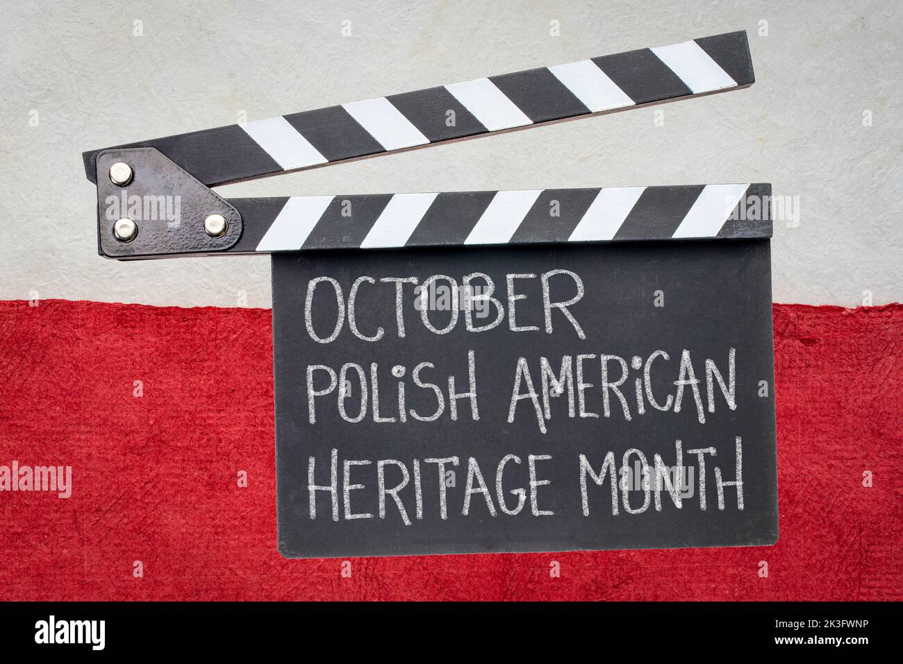 October - Polish American Heritage Month, white chalk handwriting on clapboard against a paper abstract in colors of Poland national flag, white and r Stock Photo