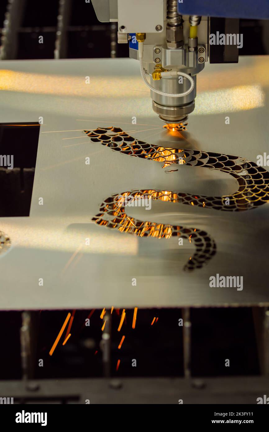 CNC laser cutting machine making holes in sheet metal with sparks Stock