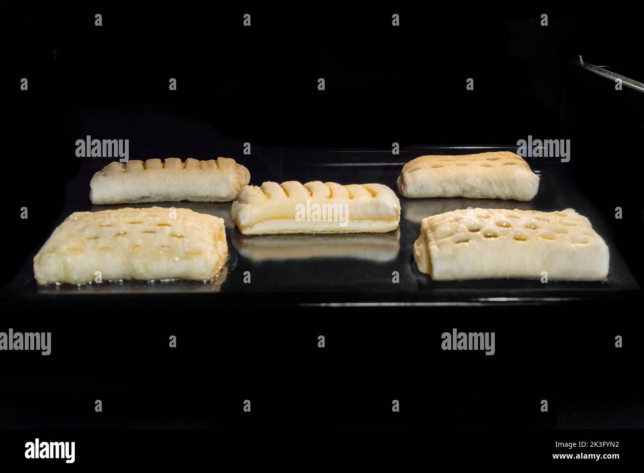 Five homemade buns with fruit jam baking in electric oven Stock Photo