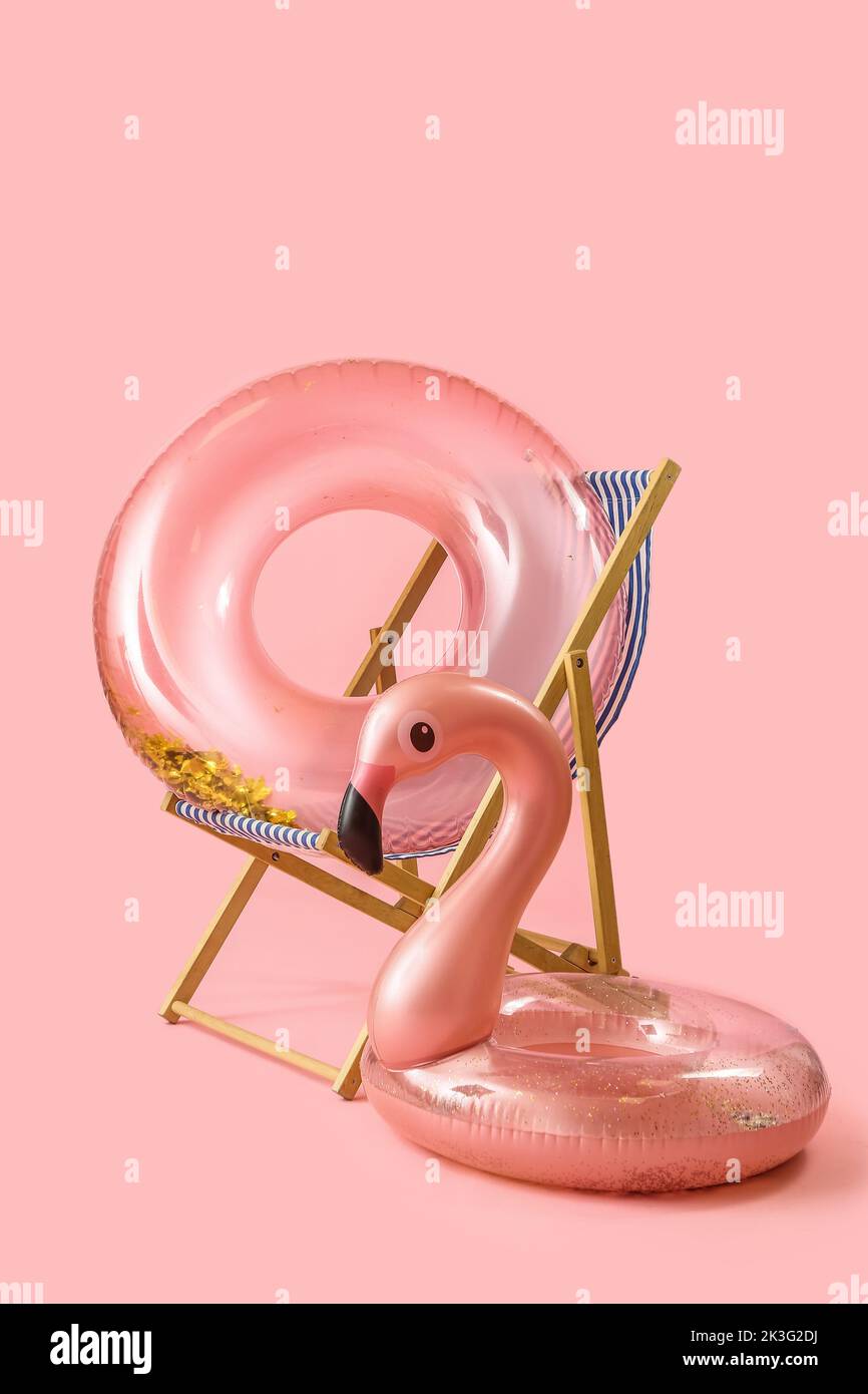 Beach deck chair and inflatable rings on pink background Stock Photo