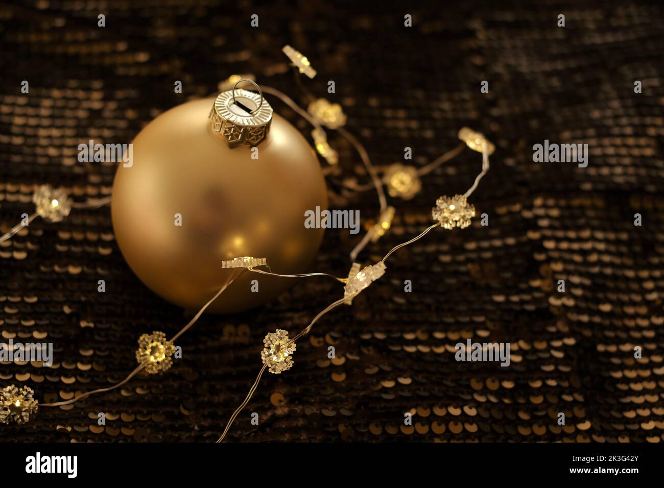Sparkling Golden balls and glowing garlands on brown sequins background.Christmas balls background.Festive background in Gold and brown tones. Stock Photo