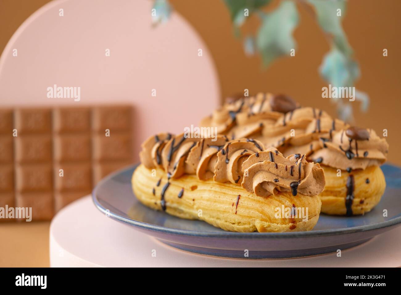 Eclairs chocolate cakes.Custard cakes with chocolate cream and chocolate bar on brown background.Sweets and desserts. Baked goods and desserts.Eclairs Stock Photo